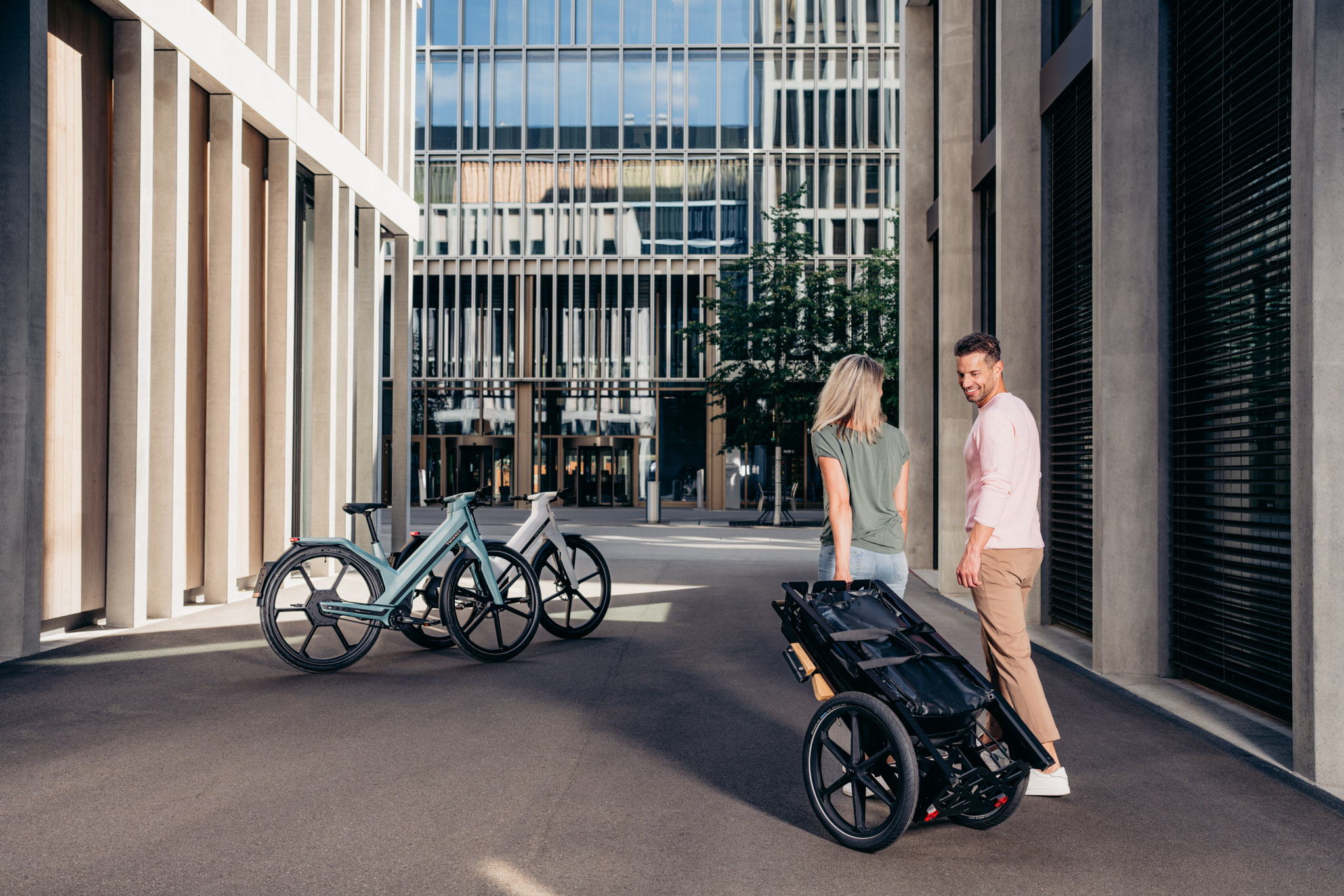 Mann und Frau mit Shopping Cart Anhänger gehen auf ihre E-Bikes zu