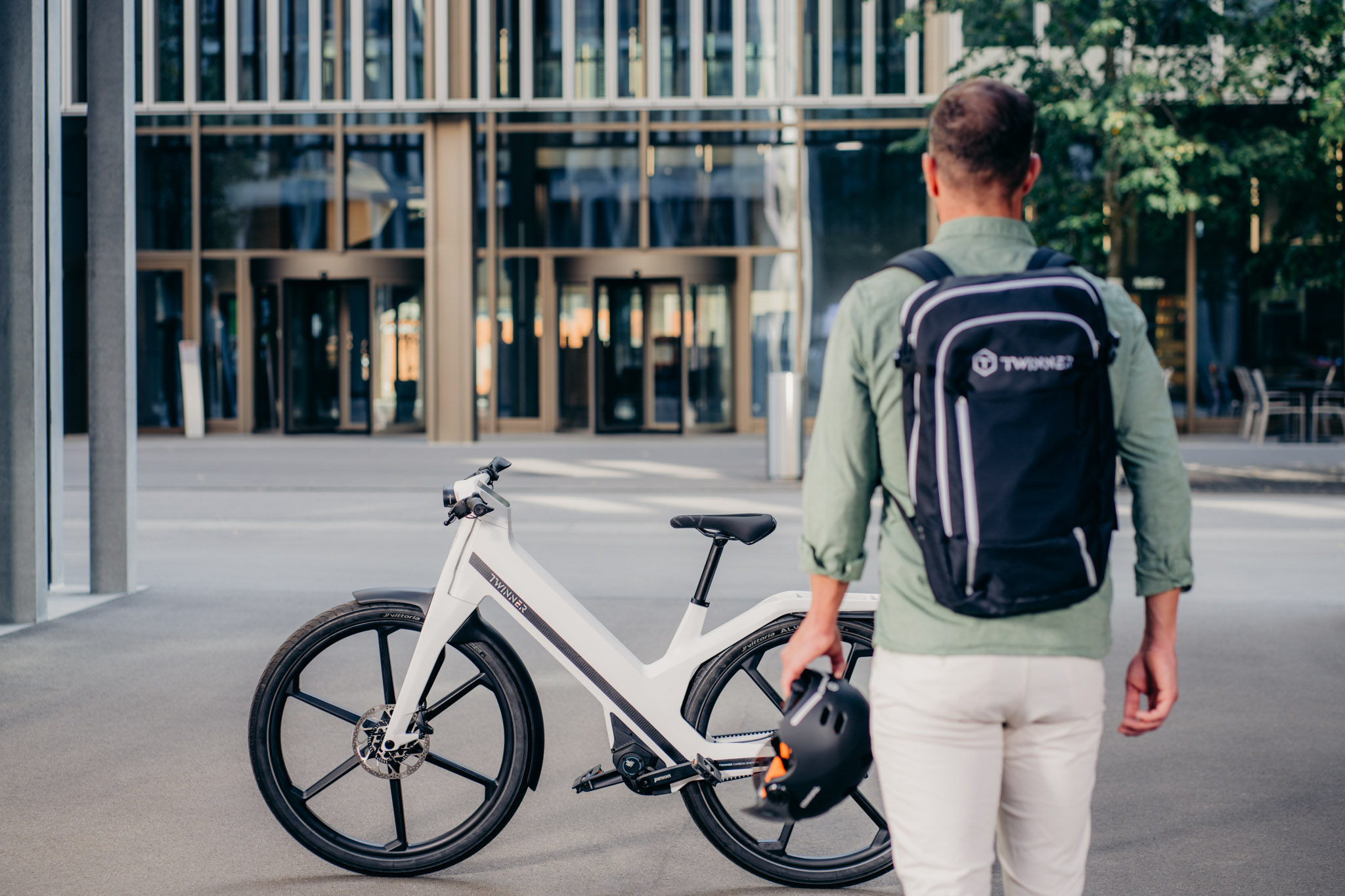 Mann mit Rucksack und Helm in der Hand geht auf sein Twinner E-Bike zu